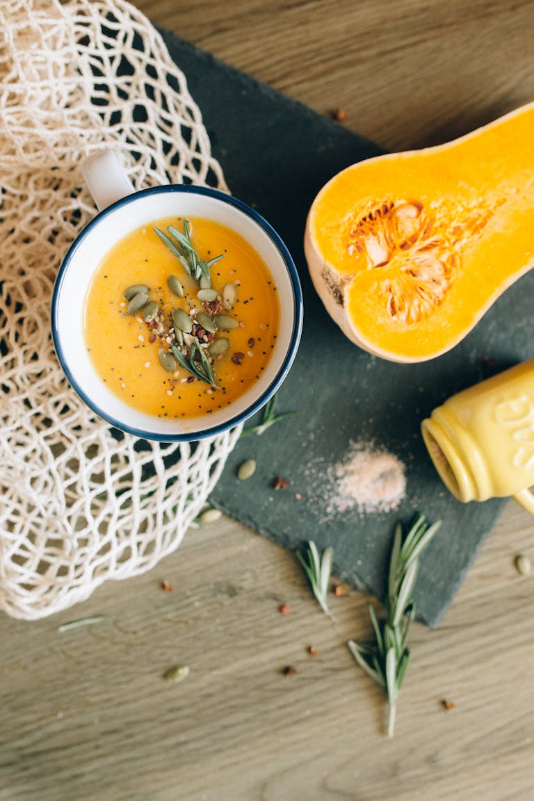 Delicious homemade butternut squash soup topped with pumpkin seeds and fresh herbs in a rustic setting.