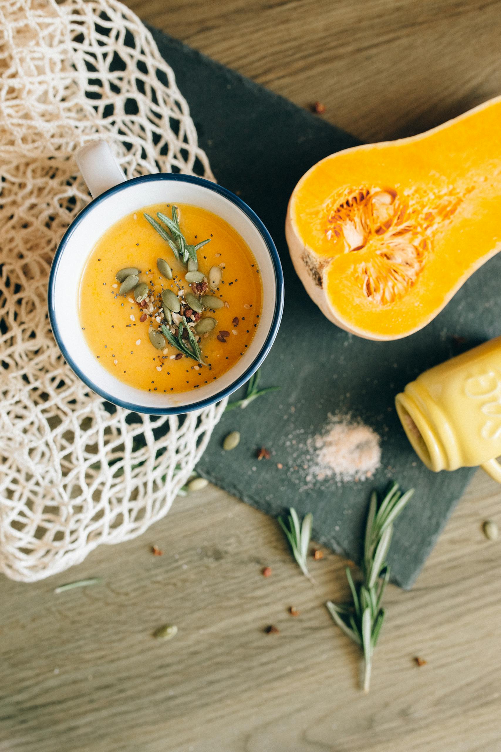 Delicious homemade butternut squash soup topped with pumpkin seeds and fresh herbs in a rustic setting.