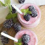 Enjoy a refreshing blackberry smoothie topped with fresh mint leaves, perfect for a summer treat.