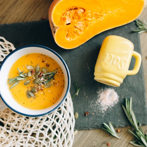 Top view of a creamy pumpkin soup garnished with seeds and rosemary, reflecting autumn flavors.